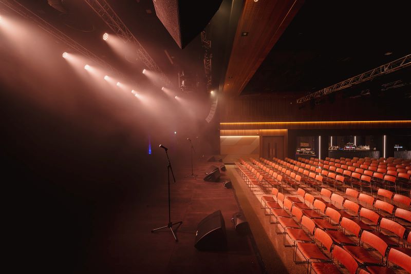 mandela hall stage with stage lighting on and chairs in the hall.